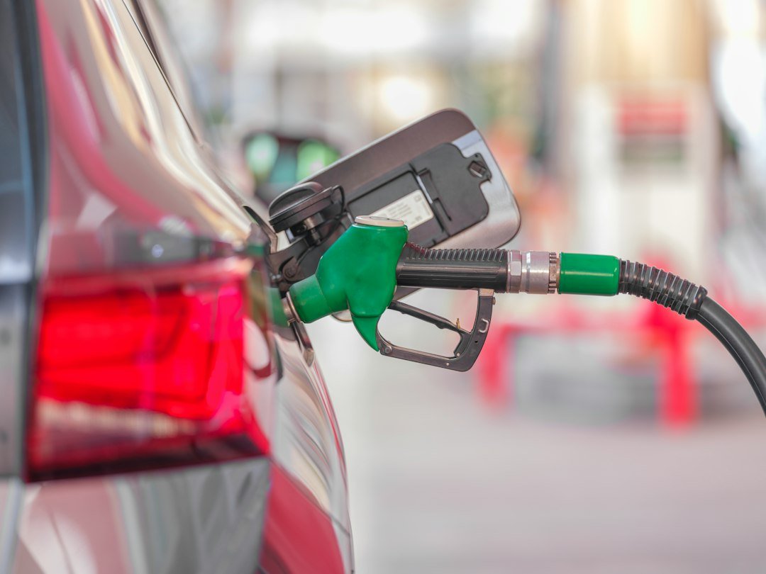 Pistolet de pompe à carburant inséré dans le réservoir d’une voiture. Photo d’engin akyurt, Unsplash.