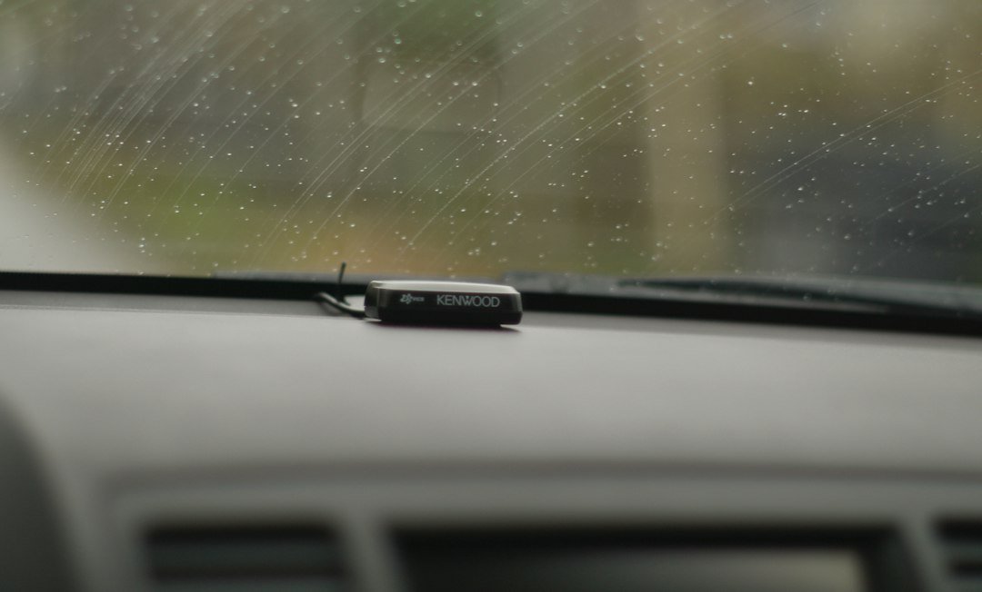 Tableau de bord vu de l'intérieur, avec de la pluie sur le pare-brise. Photo de Val Do, Unsplash.