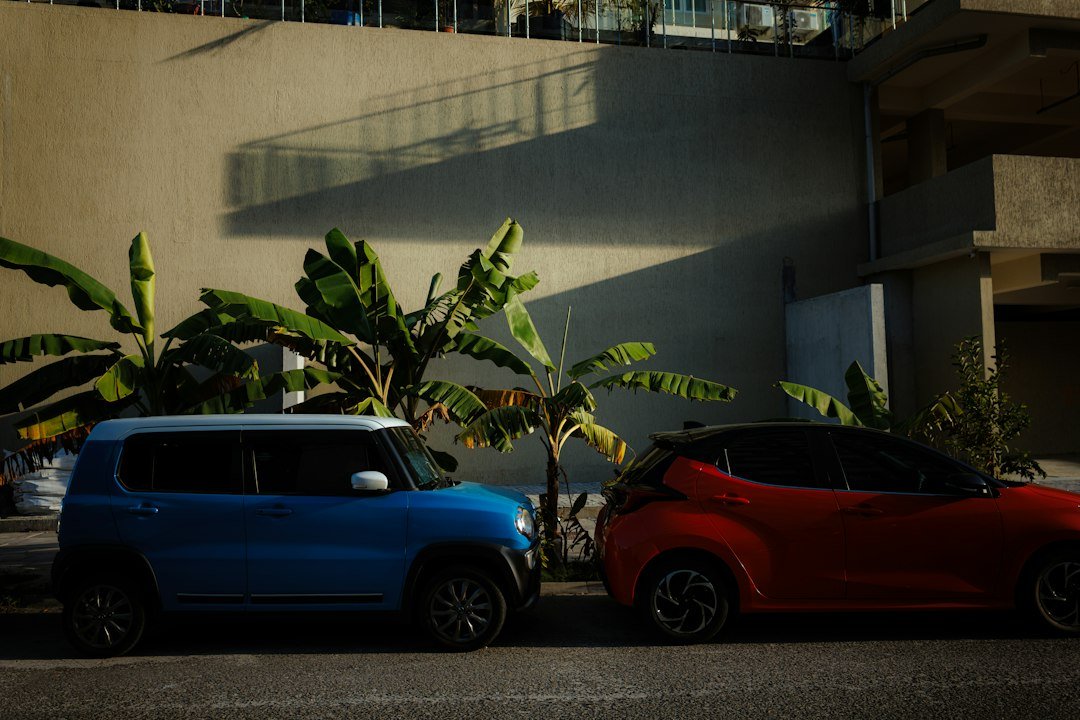 Voitures compactes garées en pleine lumière d'après-midi. Photo d'Infinara, Unsplash. Aucun enfant n'est visible.