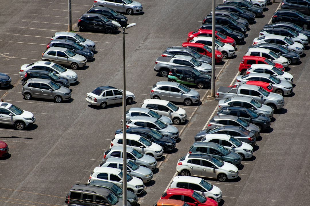 Voitures garées en rang sur un parking en plein jour. Photo de Vitor Paladini, Unsplash.