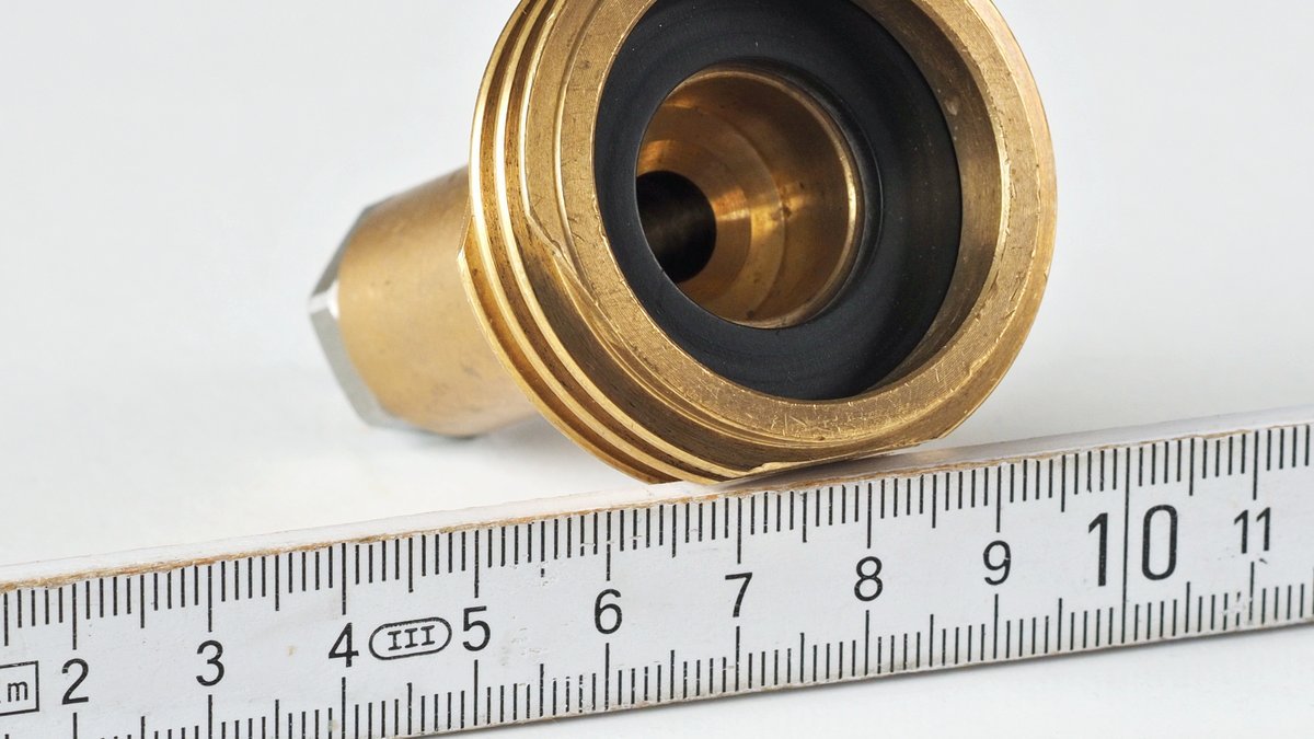 Adaptateur GPL de type ACME en laiton posé à côté d’un mètre pliant, il mesure une dizaine de centimètres