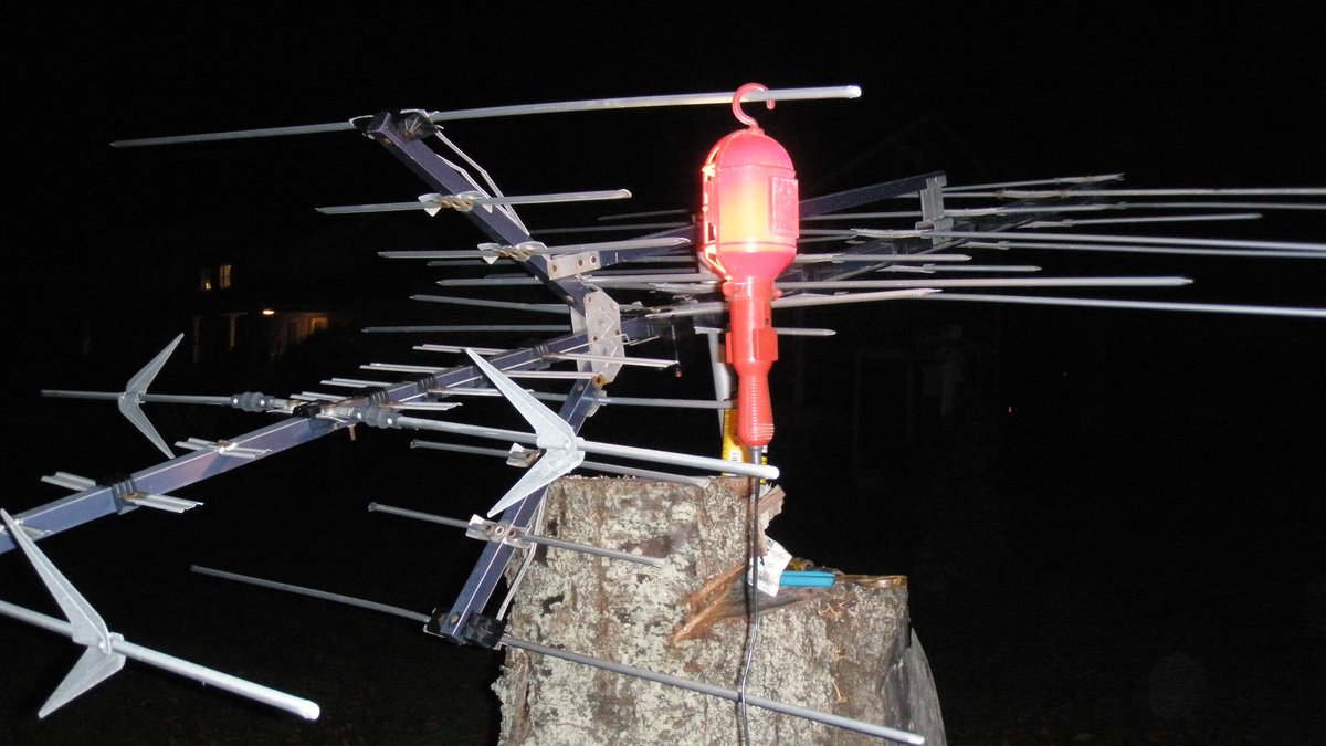 Ancienne baladeuse orange à crochet suspendue de nuit à une antenne de télévision posée sur une souche