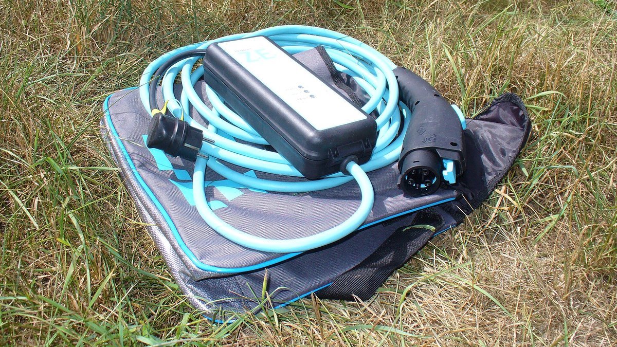 Câble de recharge mode 2 d'une Renault Fluence Z.E. avec son boîtier de contrôle et sa fiche pour prise domestique, posé sur une housse dans l'herbe