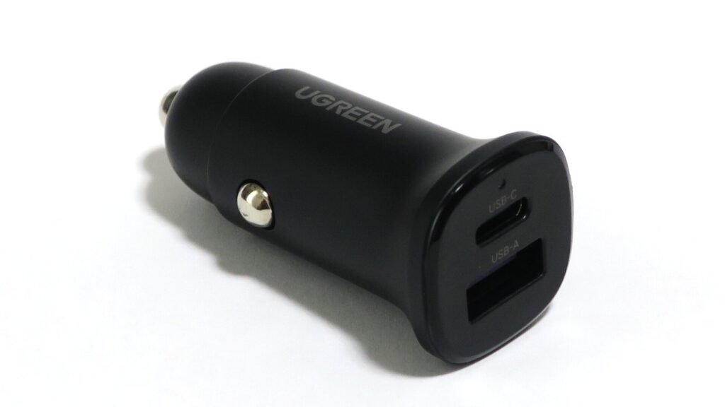 Chargeur de voiture noir pour prise allume-cigare, avec un port USB-C et un port USB-A en façade, posé sur fond blanc