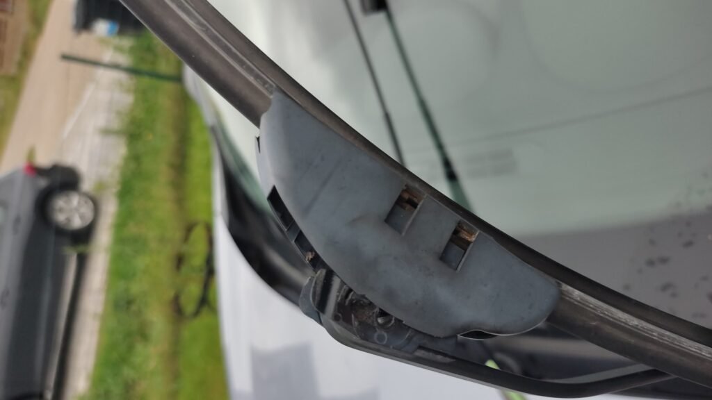Gros plan d’un balai d’essuie-glace plat relevé sur le pare-brise d’une Renault Mégane III, attache à crochet visible, photo d’illustration