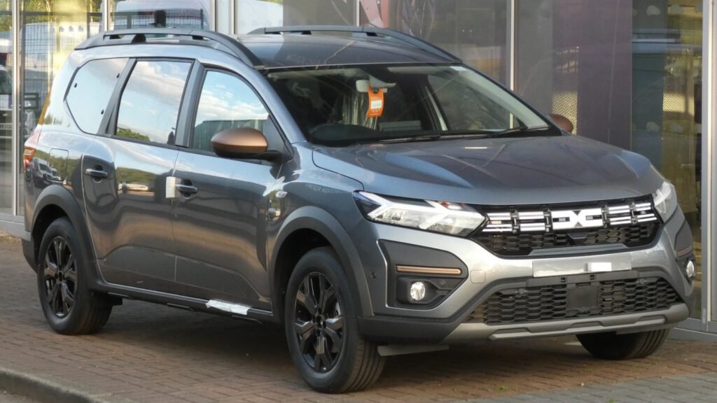 Dacia Jogger Hybrid gris vue de trois quarts avant, garée devant une concession, illustration d’une voiture hybride non rechargeable