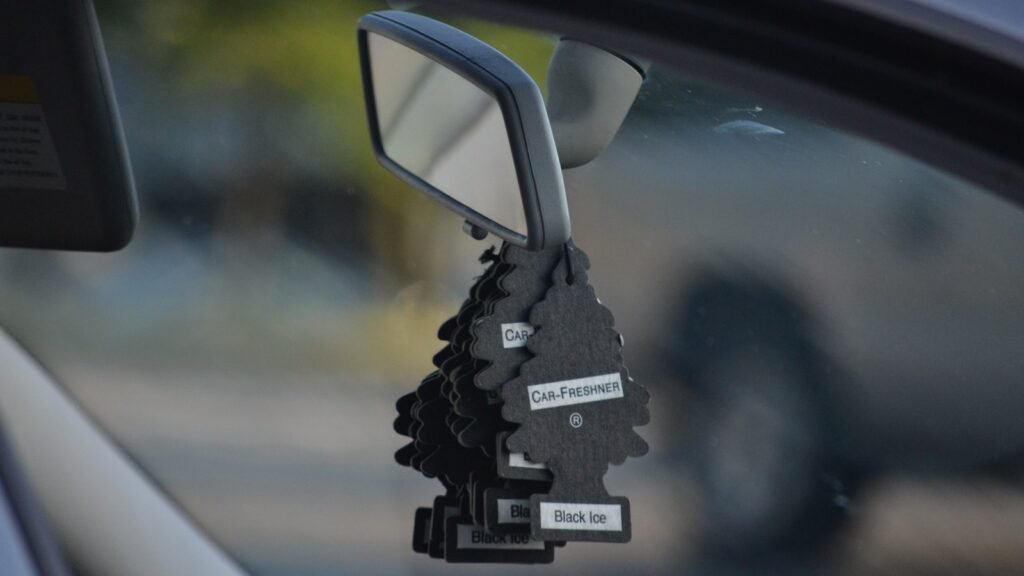 Plusieurs désodorisants noirs en forme de sapin accrochés au rétroviseur intérieur d’une voiture