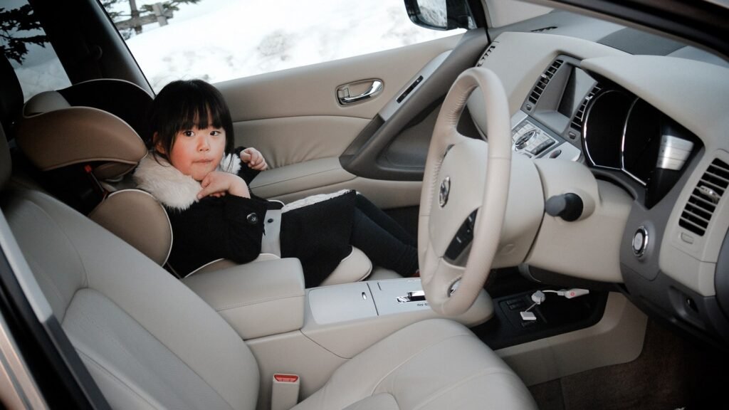 Enfant assis à la place avant passager d’une voiture, ceinture attachée — photo d’illustration