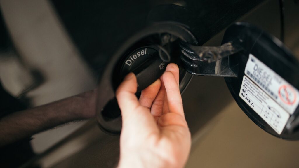Main qui introduit un pistolet de carburant dans l'orifice diesel d'une voiture à une station-service, en plein jour