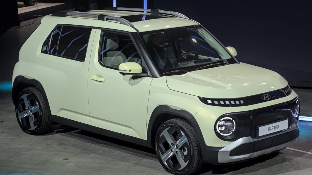Hyundai Inster vert pâle exposée sur le stand d'un salon automobile, vue de trois quarts avant