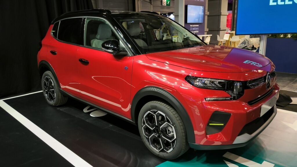 Citroën ë-C3 électrique rouge à toit noir exposée sur un stand du Mondial de l’automobile de Paris, vue de trois quarts avant