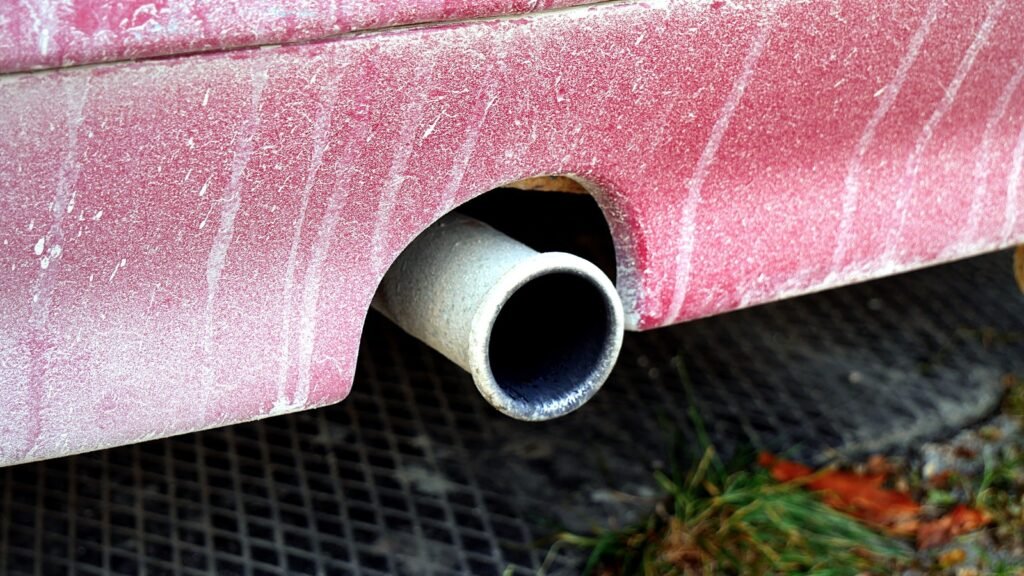 Gros plan sur un pot d’échappement chromé sous l’arrière d’une voiture rouge, illustration des risques de monoxyde de carbone