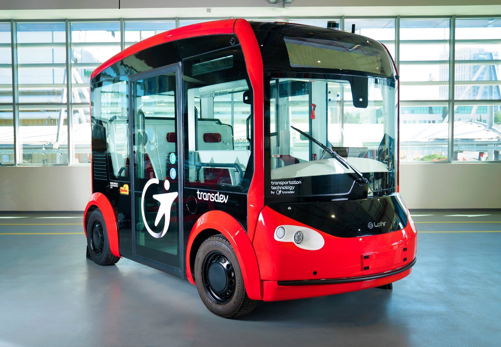 Navette autonome électrique rouge i-Cristal de Lohr et Transdev, sans volant, exposée dans un hall vitré