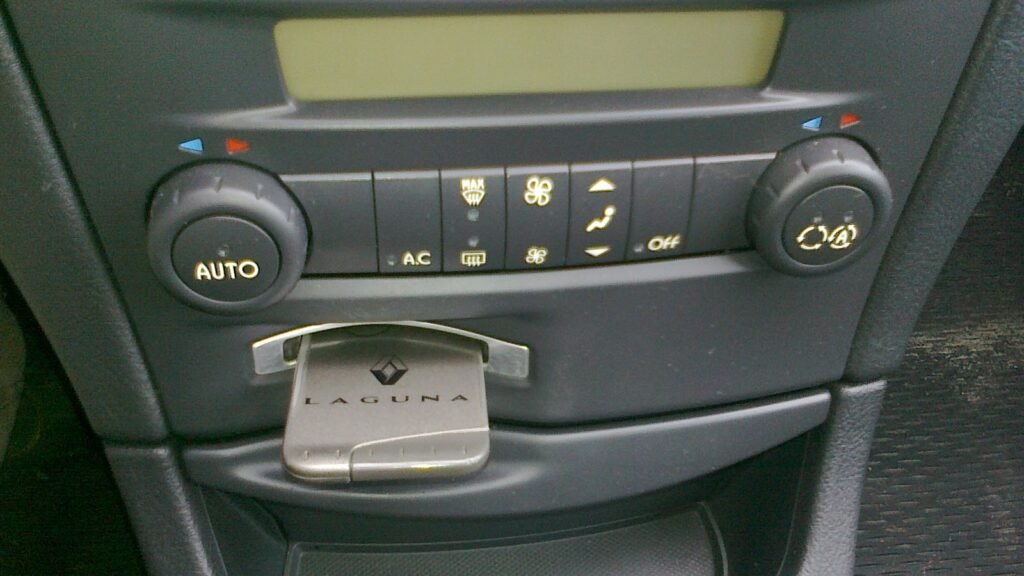 Planche de bord : boutons de climatisation automatique et chauffage d’une Renault Laguna, carte main libre dans le lecteur