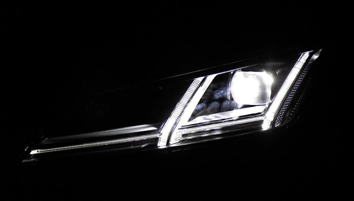 Phare LED matriciel d’une Audi TT allumé dans le noir, avec sa lentille de projection et sa signature lumineuse de jour