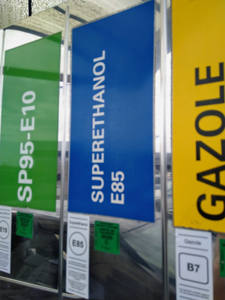 Pistolets d’une station-service française surmontés de trois étiquettes de couleur : SP95-E10 en vert, Superéthanol E85 en bleu et Gazole en jaune