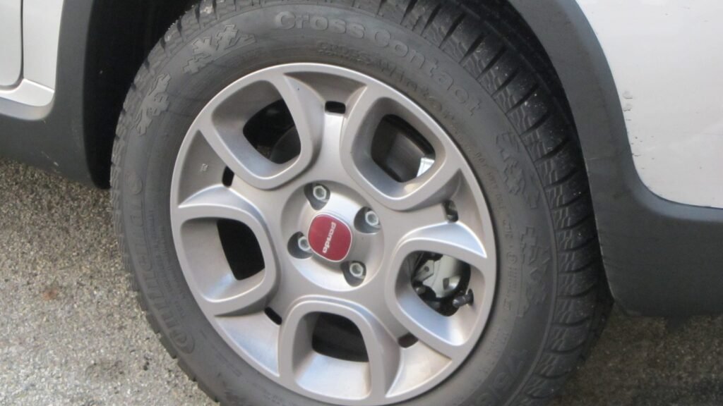 Roue avant d'une Fiat Panda 4x4 équipée de pneus neige, sur fond enneigé en Italie