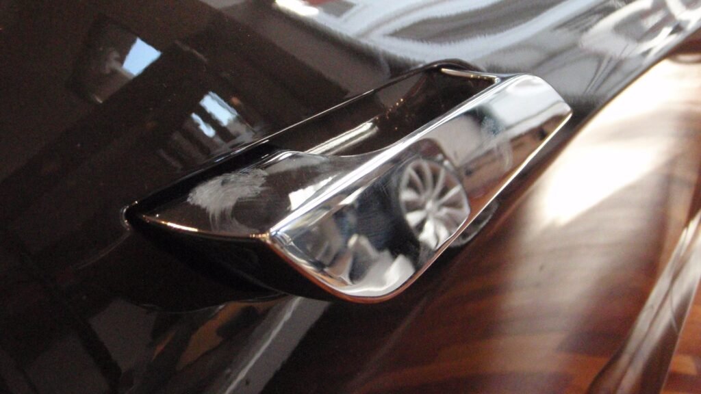 Poignée de porte affleurante chromée d’une Tesla Model S en position sortie, sur une carrosserie sombre
