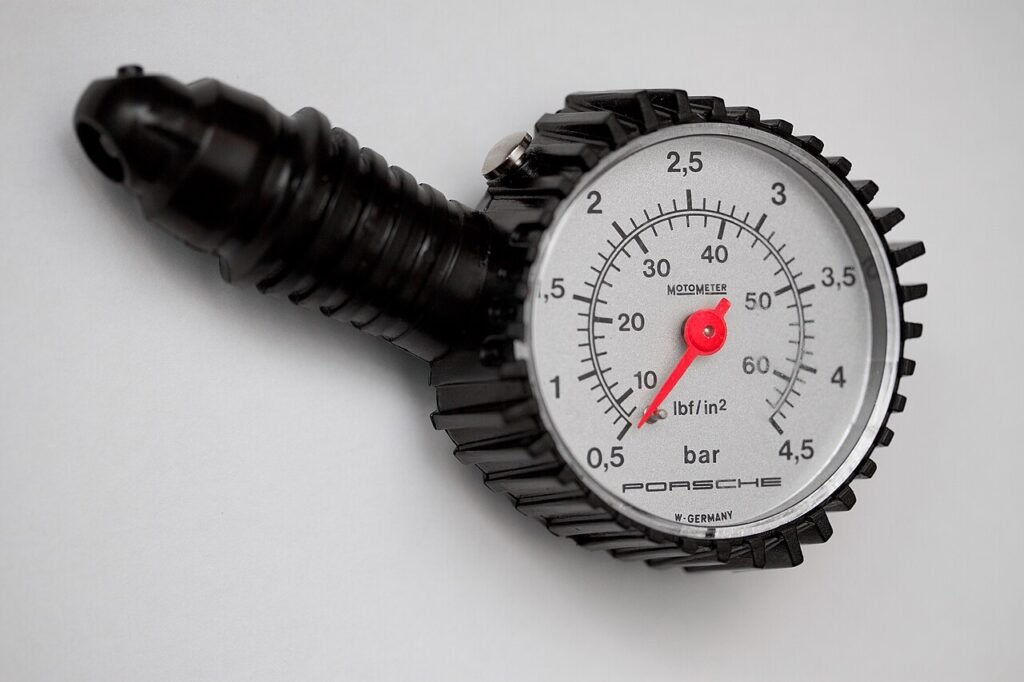 Manomètre à aiguille rouge pour pneus de voiture, gradué en bar et en psi, posé sur un fond gris clair