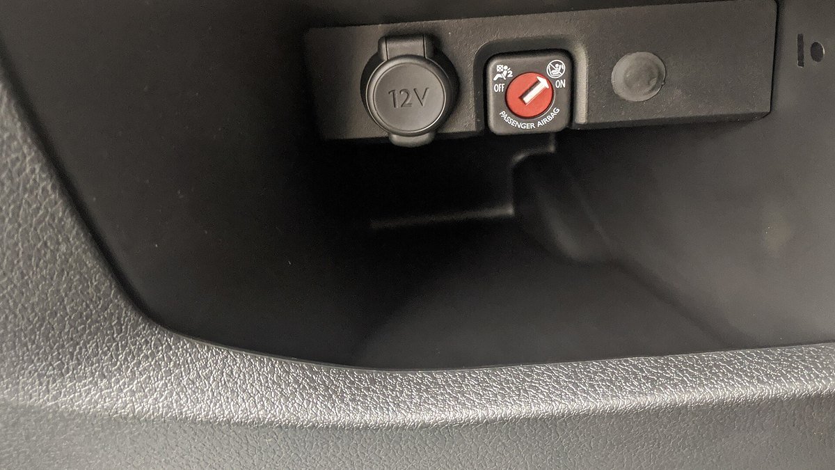 Prise 12 V à capuchon dans la console d’un Peugeot Traveller, à côté de la clé de désactivation de l’airbag passager