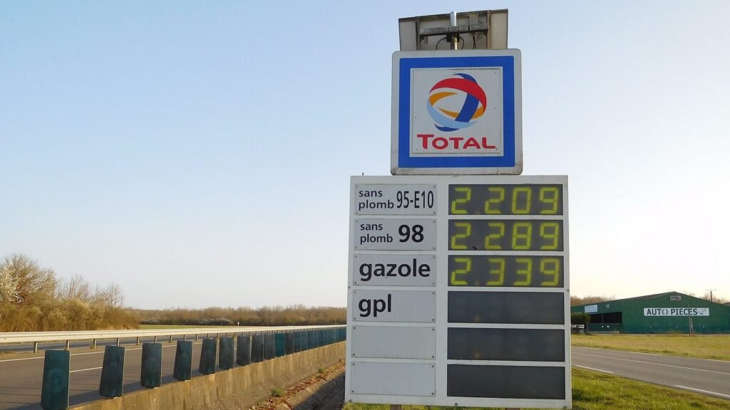 Totem de prix des carburants Total au bord de l’autoroute A77, affichant le sans plomb 95-E10, le sans plomb 98 et le gazole, avec la glissière de l’autoroute à gauche et un ciel bleu