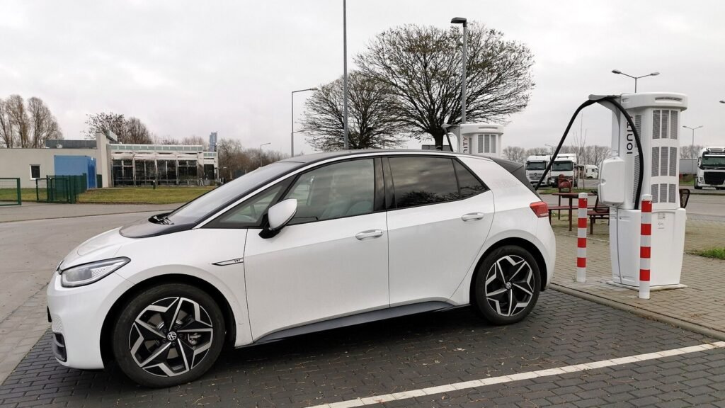 Volkswagen ID.3 blanche garée devant une borne de recharge rapide Ionity sur une aire d’autoroute, sous un ciel gris d’hiver