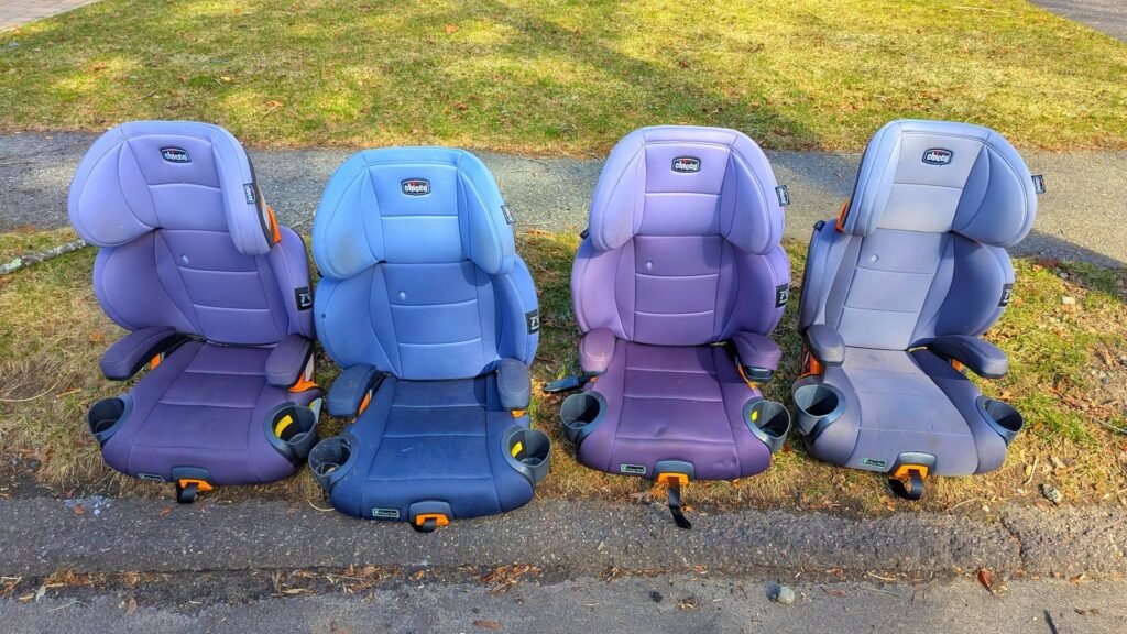 Quatre rehausseurs pour enfants, bleus et violets, alignés côte à côte sur une pelouse