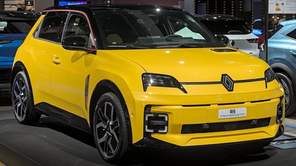 Renault 5 E-Tech électrique jaune au toit noir, vue de trois quarts avant, exposée sur un stand de salon automobile
