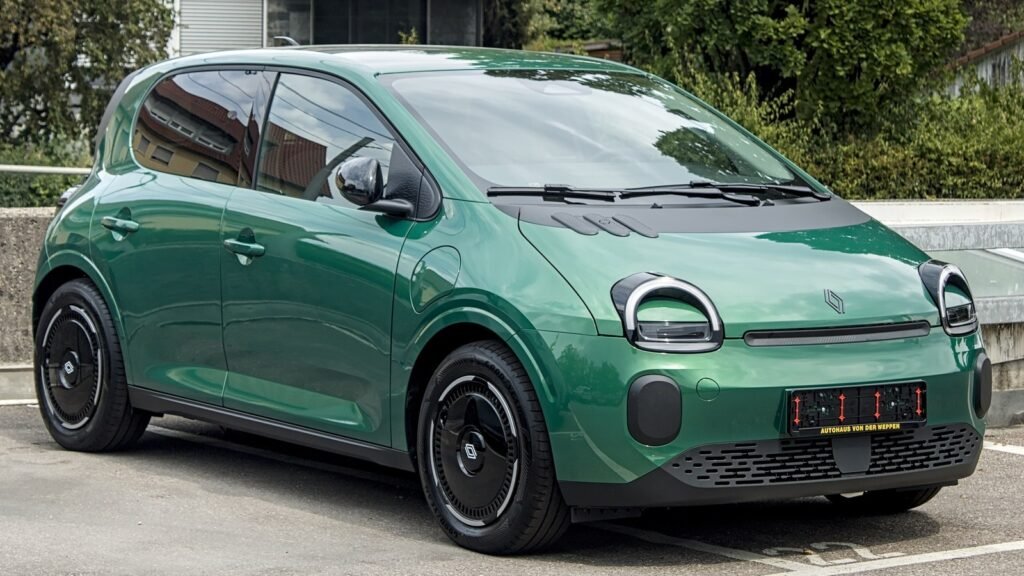 Une Renault Twingo E-Tech électrique verte garée sur un parking, vue de trois quarts avant, avec ses phares ronds et sa face avant souriante
