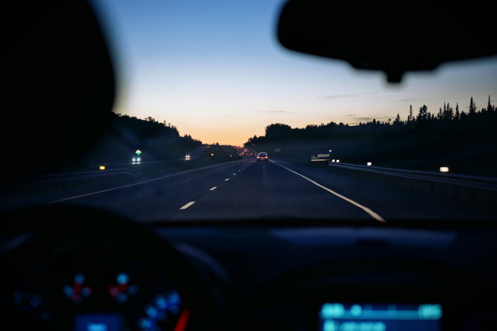 Vue depuis la place du conducteur sur une route au crépuscule, tableau de bord allumé