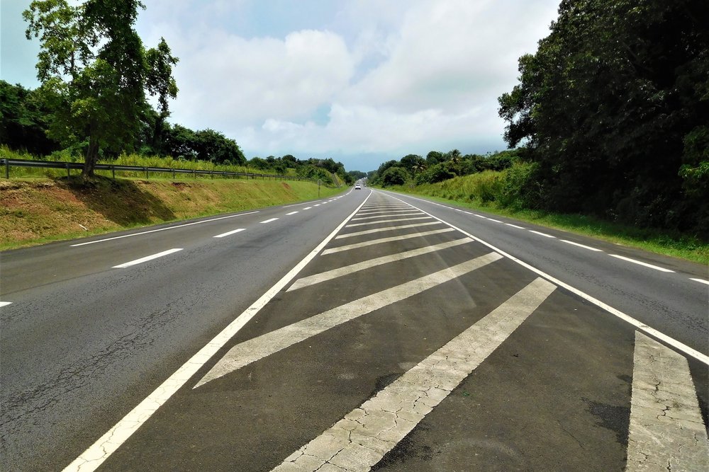 Route nationale 1 de Guadeloupe, déserte, bordée de végétation tropicale sous un ciel nuageux