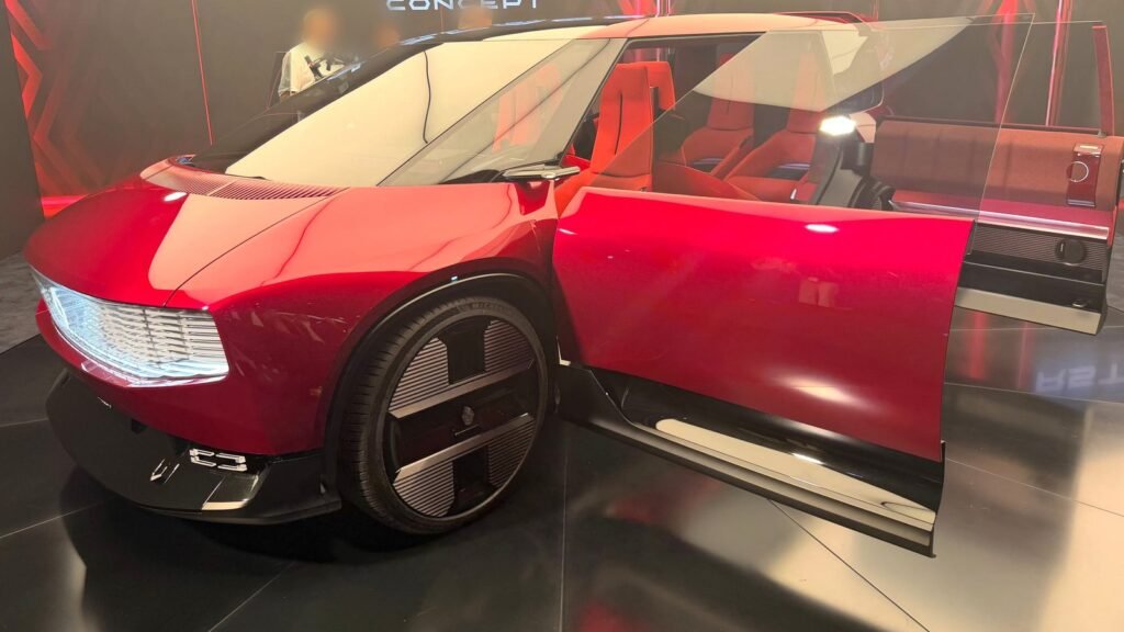 Le concept Renault E-Space rouge exposé au Mondial de l’Auto 2026 à Paris, portière avant grande ouverte sur un intérieur rouge, grandes jantes carénées et bandeau lumineux à l’avant, sur un stand sombre