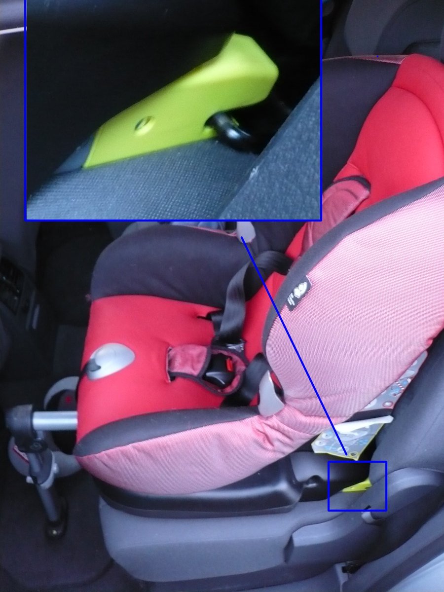 Siège auto enfant rouge installé à l'arrière d'une voiture, avec jambe de force au plancher et zoom sur un point d'ancrage Isofix entre l'assise et le dossier