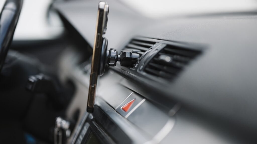 Smartphone fixé par un support magnétique à la grille d’aération du tableau de bord d’une voiture