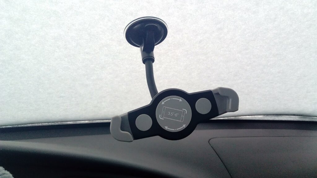 Support de téléphone universel à ventouse et col de cygne fixé en bas d’un pare-brise couvert de neige, au-dessus du tableau de bord