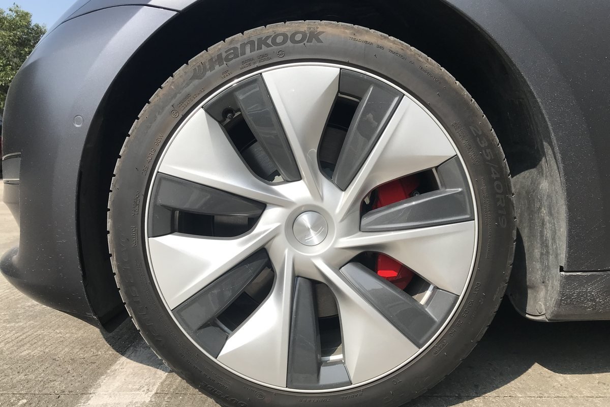 Roue d’une Tesla Model 3 grise avec enjoliveur aérodynamique et pneu Hankook en 235/40 R19, dimension lisible sur le flanc