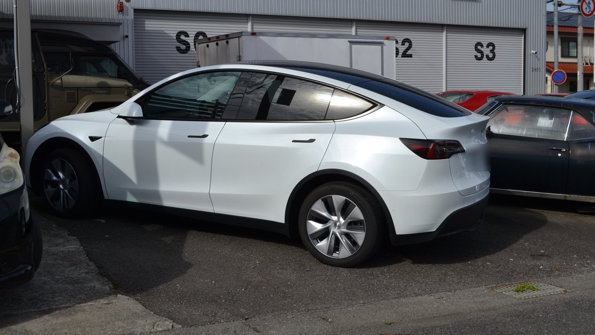 Tesla Model Y blanche garée, vue de côté, avec ses poignées de porte intégrées à la carrosserie