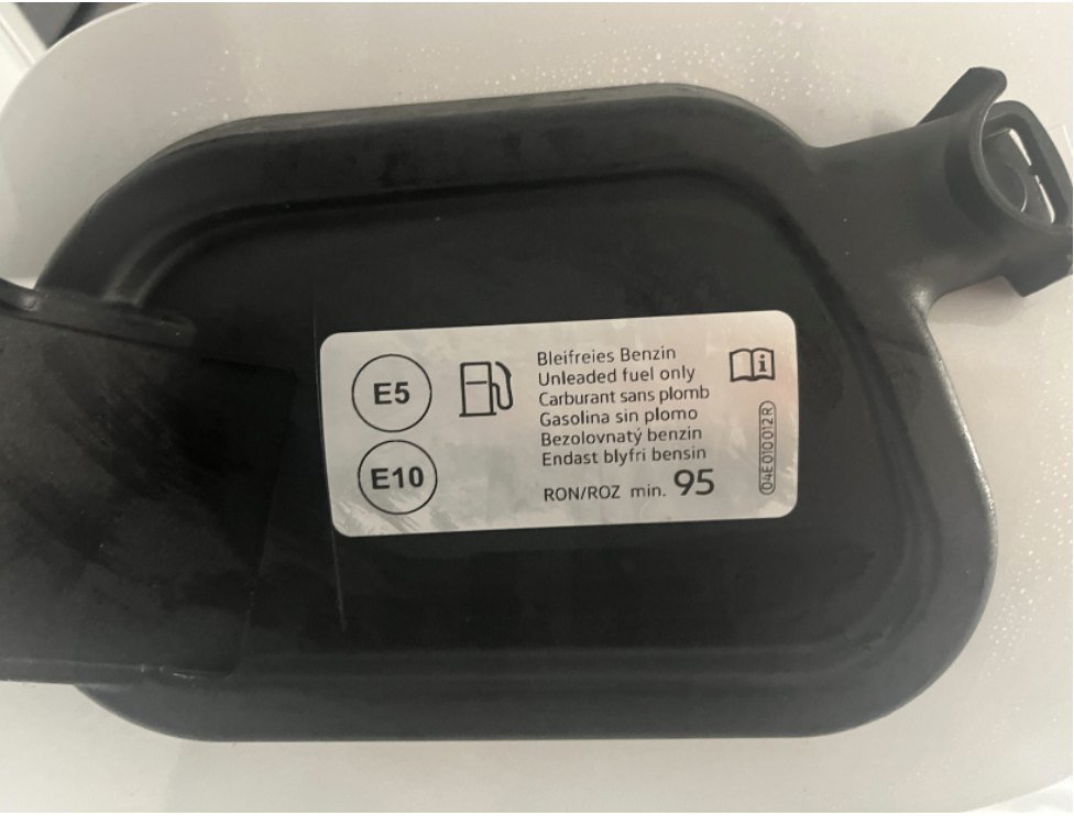 Intérieur d’une trappe à carburant de voiture avec l’étiquette ronde E5 et E10 et la mention d’un indice d’octane minimum de 95
