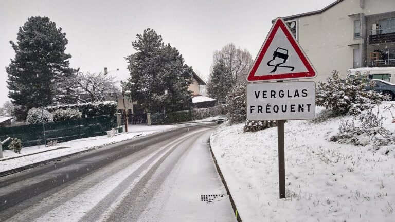 Route enneigée en hiver avec un panneau triangulaire chaussée glissante et le panonceau « Verglas fréquent », à Cranves-Sales en Haute-Savoie