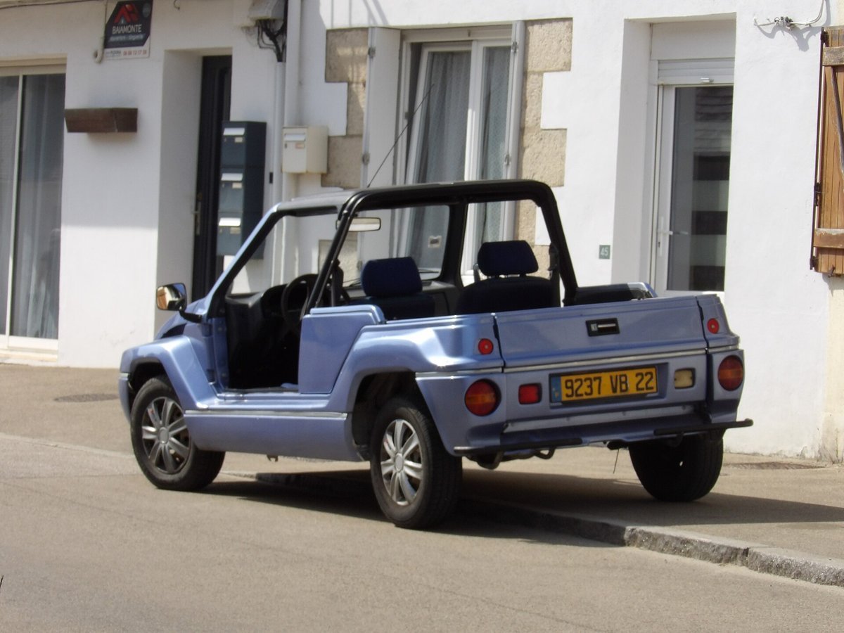 Petite voiture découvrable bleue garée devant une maison en pierre à Bréhec, en Bretagne, vue de l’arrière avec sa plaque d’immatriculation
