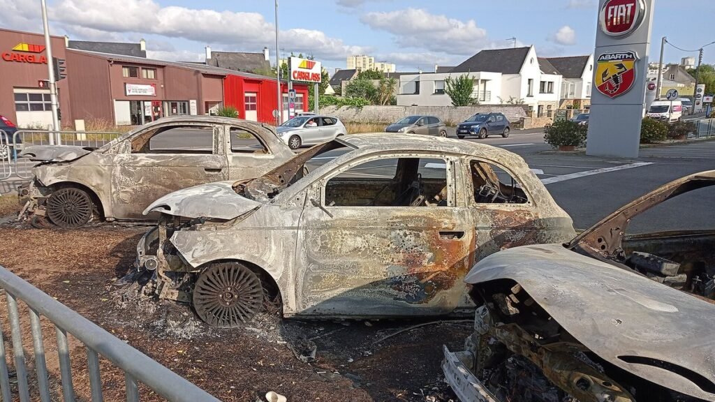 Voitures calcinées stationnées devant une concession automobile Fiat à Brest après des manifestations en 2023