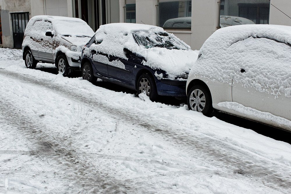 Voitures en stationnement dans une rue parisienne, sous la neige